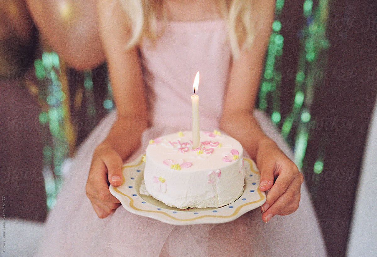 A birthday girl holding a cake with a candle.