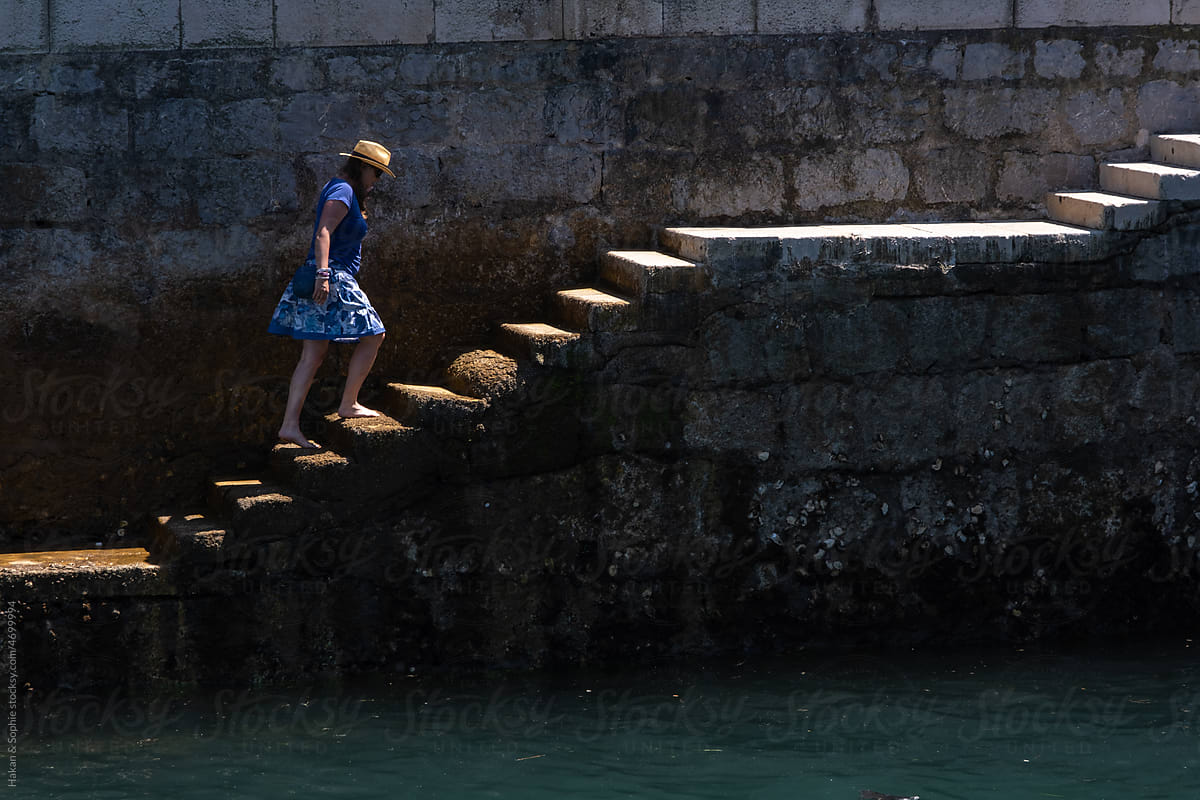 woman walks up quay stairs barefoot