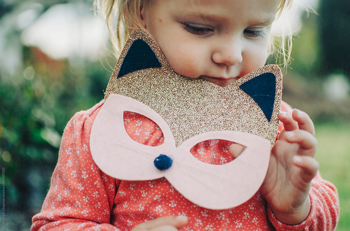 Little girl holding glitter cat mask