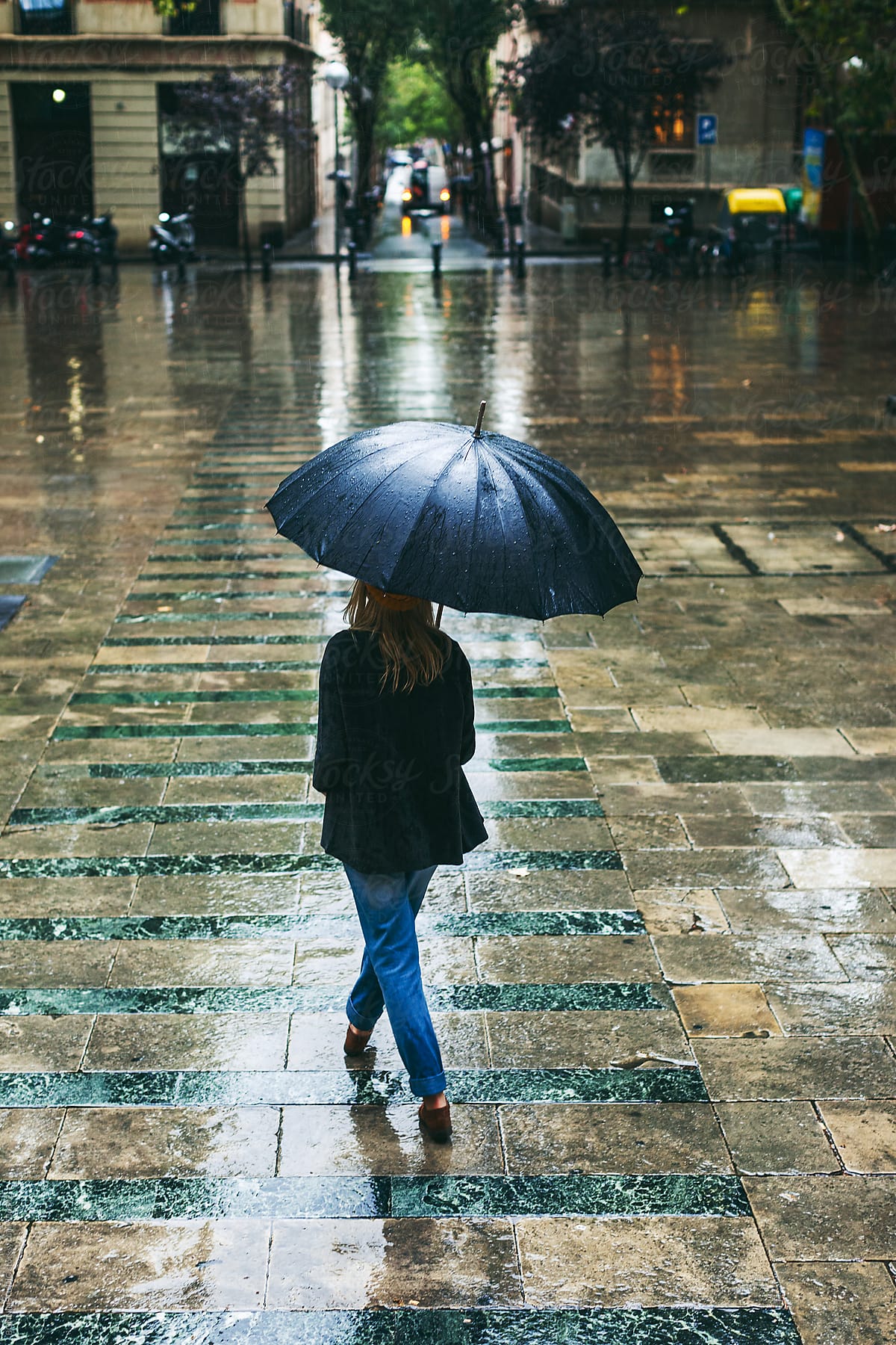 "Back View Of A Woman Walking On The Street In A Rainy Day." by Stocksy