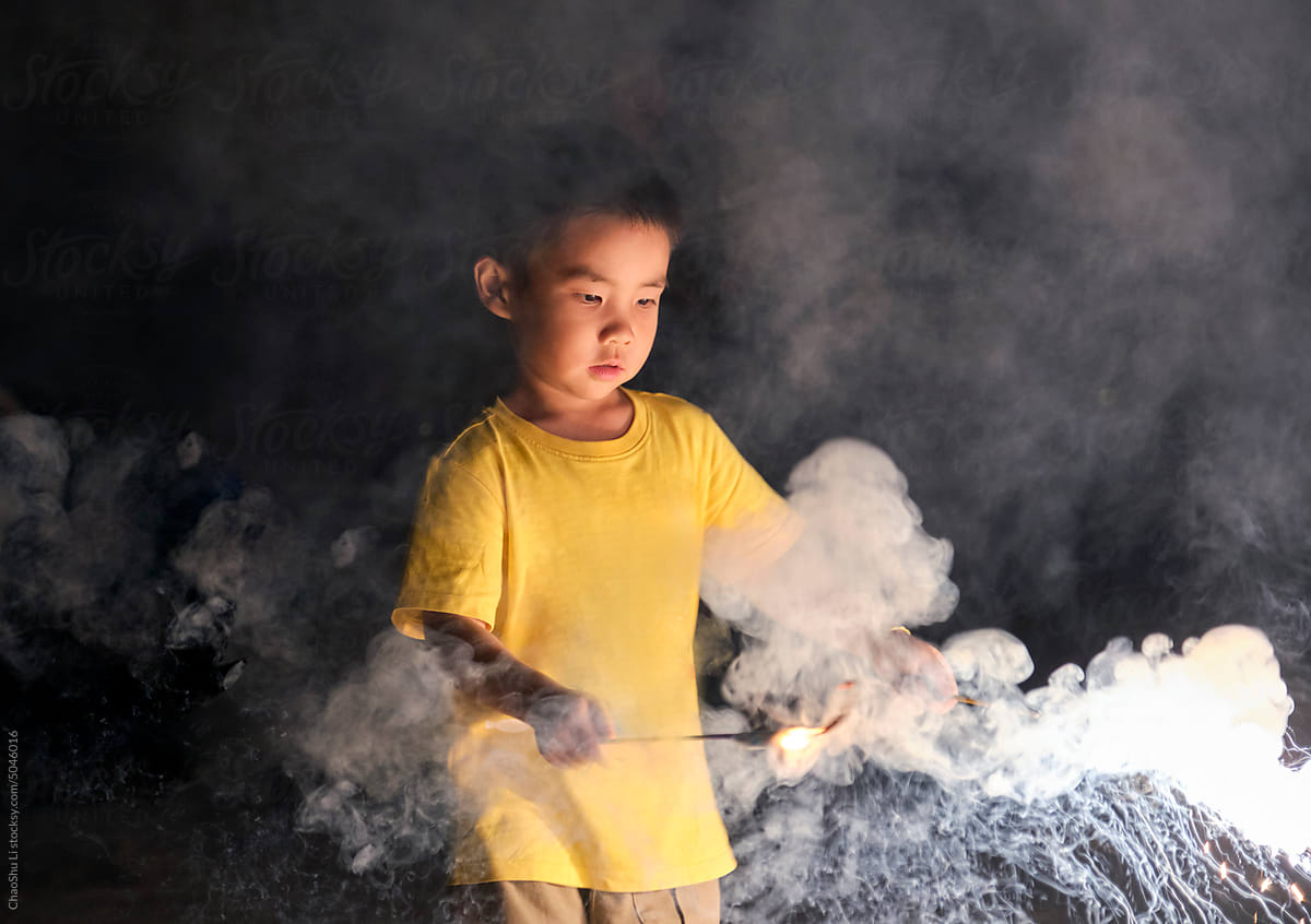 Asian little boy, playing with firework at night in nature outdoors