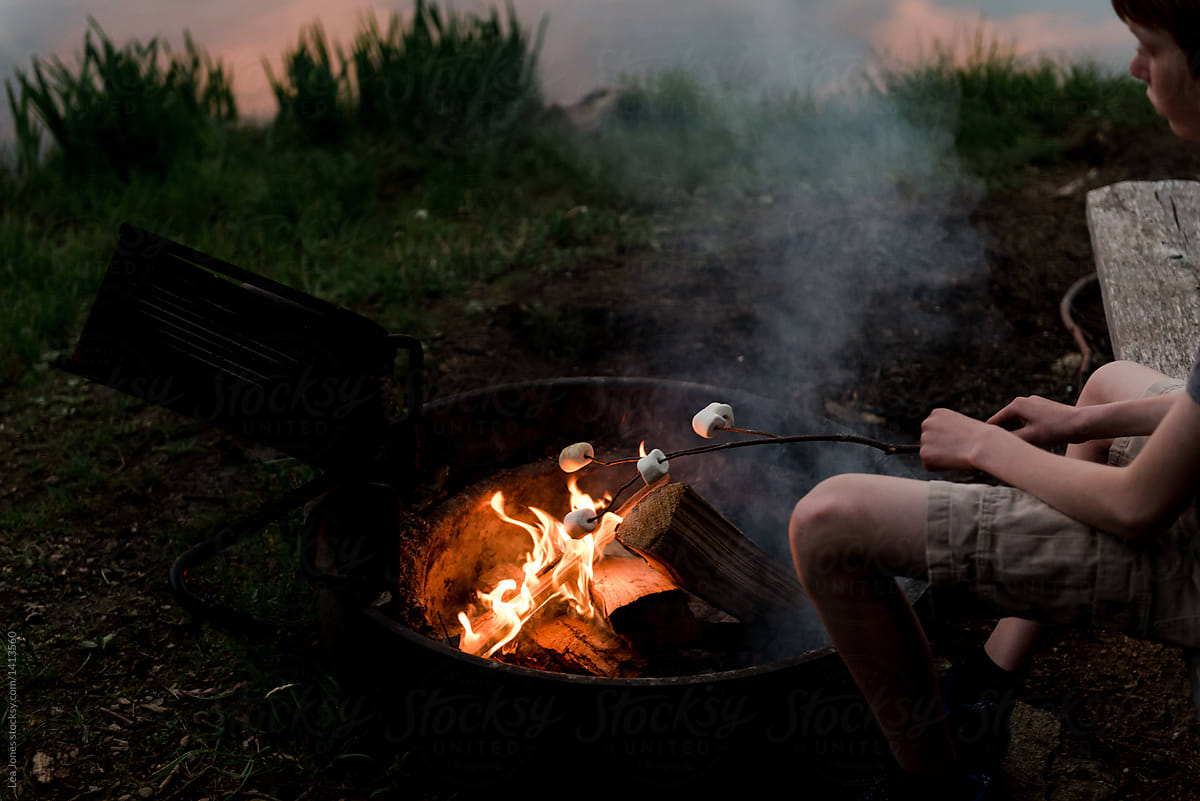 teen boy grilling 5 marshmallows on campfire