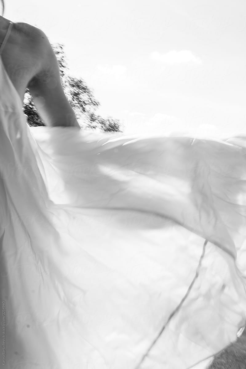 black and white photo of a girl in a light flying dress that develops in the wind against the background of the lake
