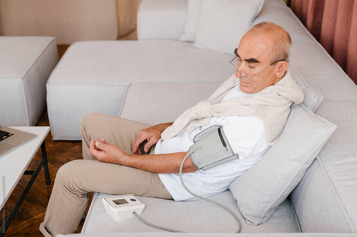 Senior man measuring blood pressure at home
