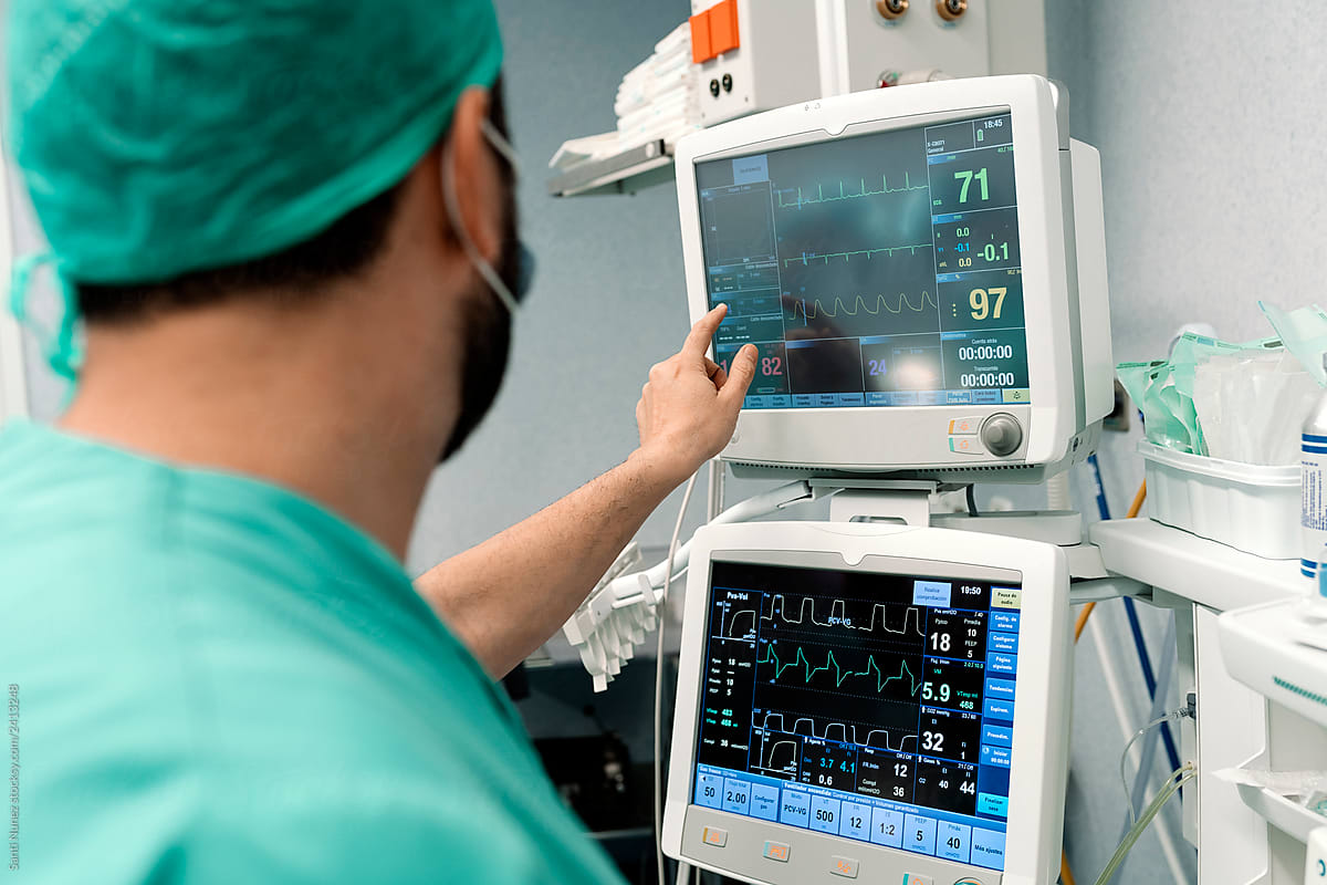 Doctor looking at monitors with pulse of patient