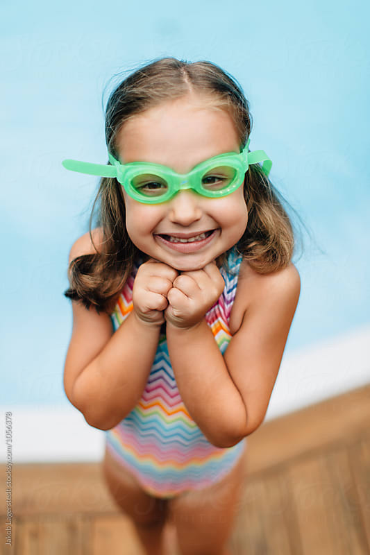 Portrait of a cute and sassy girl in swim goggles standing by a pool