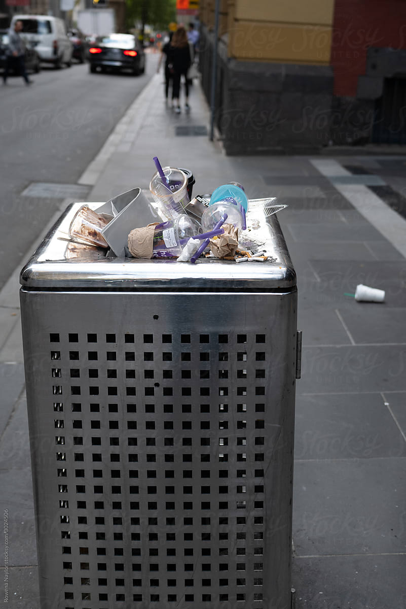 Overflowing trash bin in city filled with recyclable products
