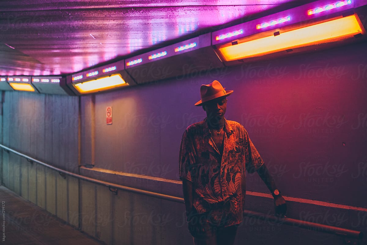 Portrait of a young black under a subway with changing lights.