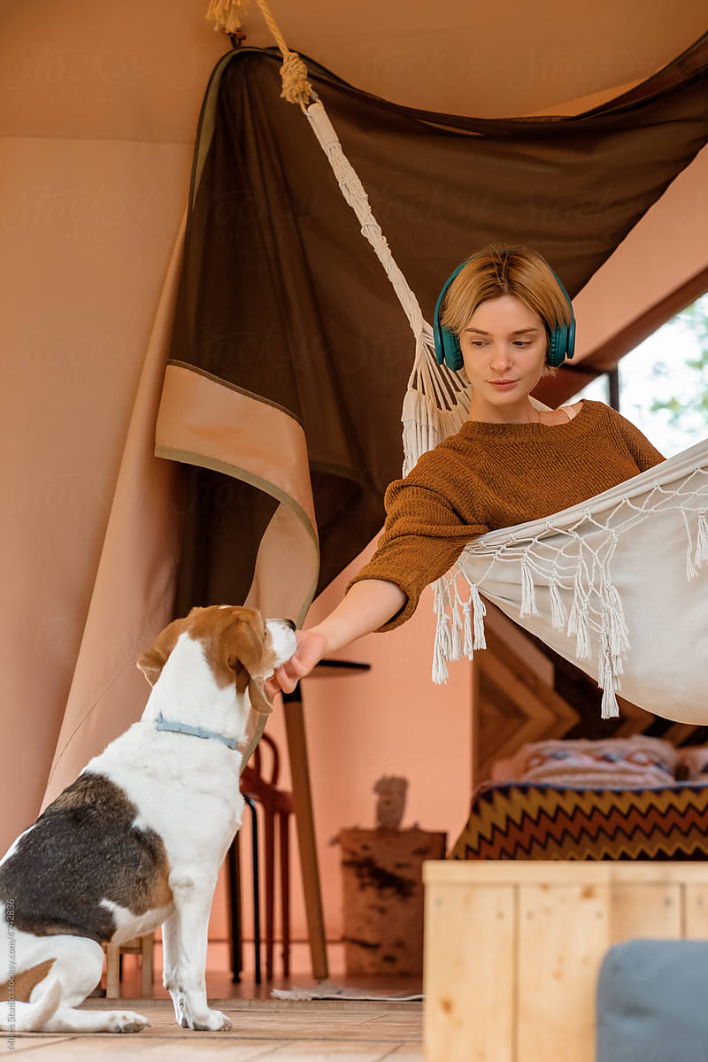 Woman resting in hammock and caressing dog