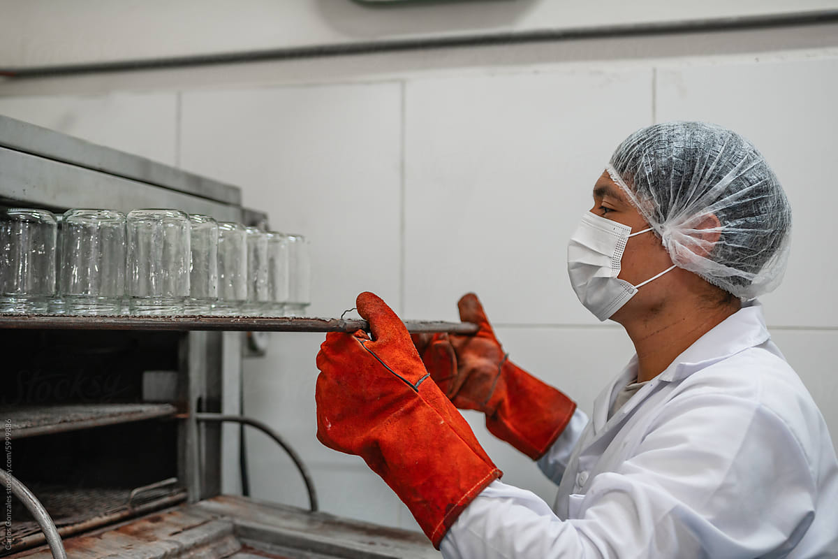 Worker Placing Glass Containers into a Sterilization Oven