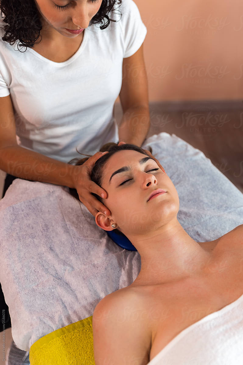 Crop masseuse doing head massage to client