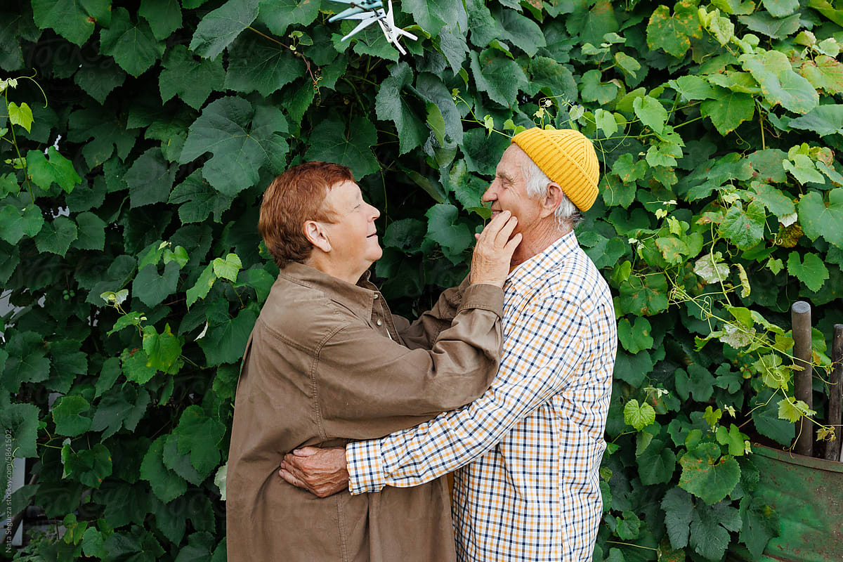 Elderly Couple Embracing in Garden During Summer