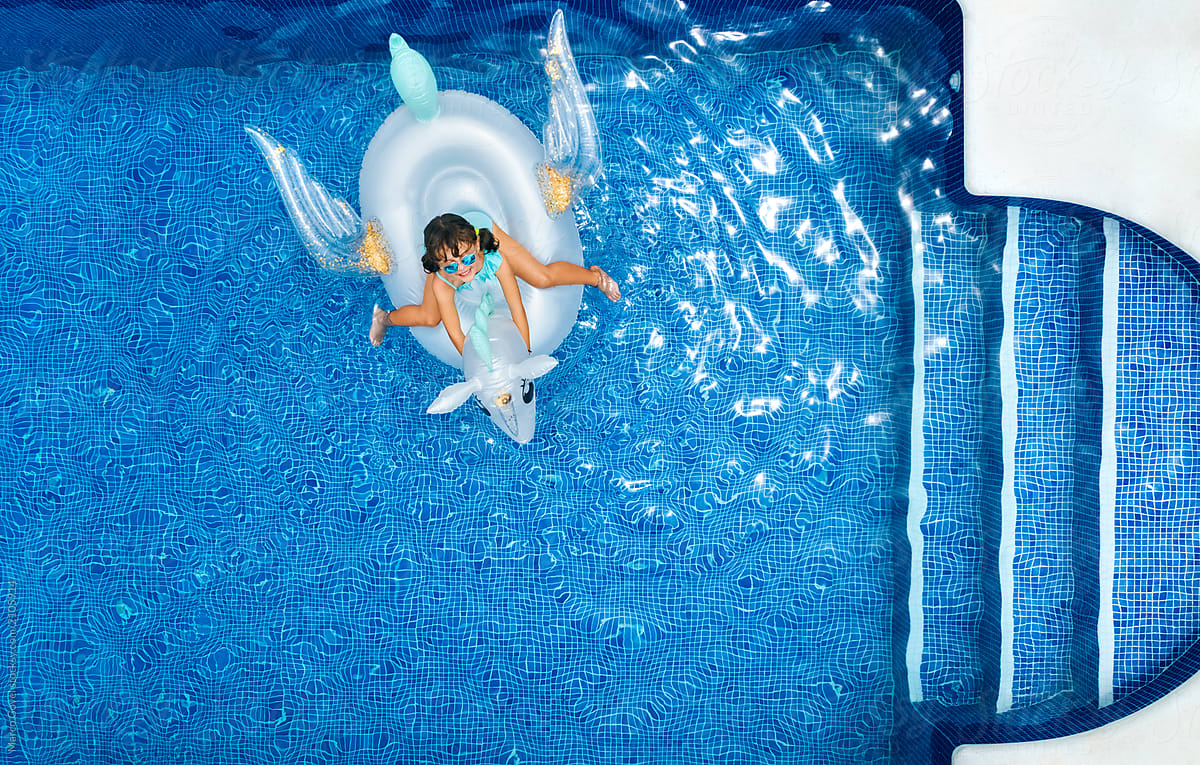Little girl on a unicorn shaped float in a swimming pool