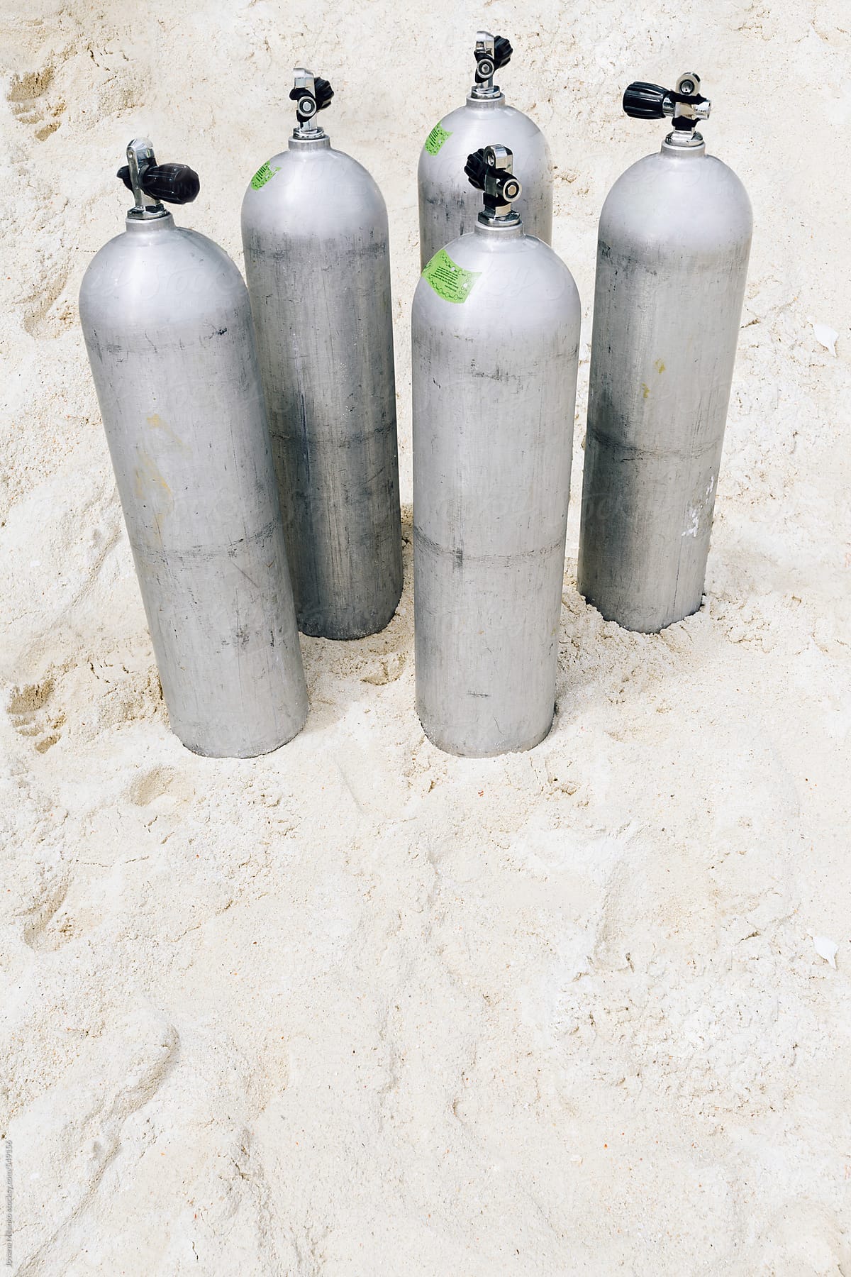Five aluminum, air scuba diving tanks on the sandy beach