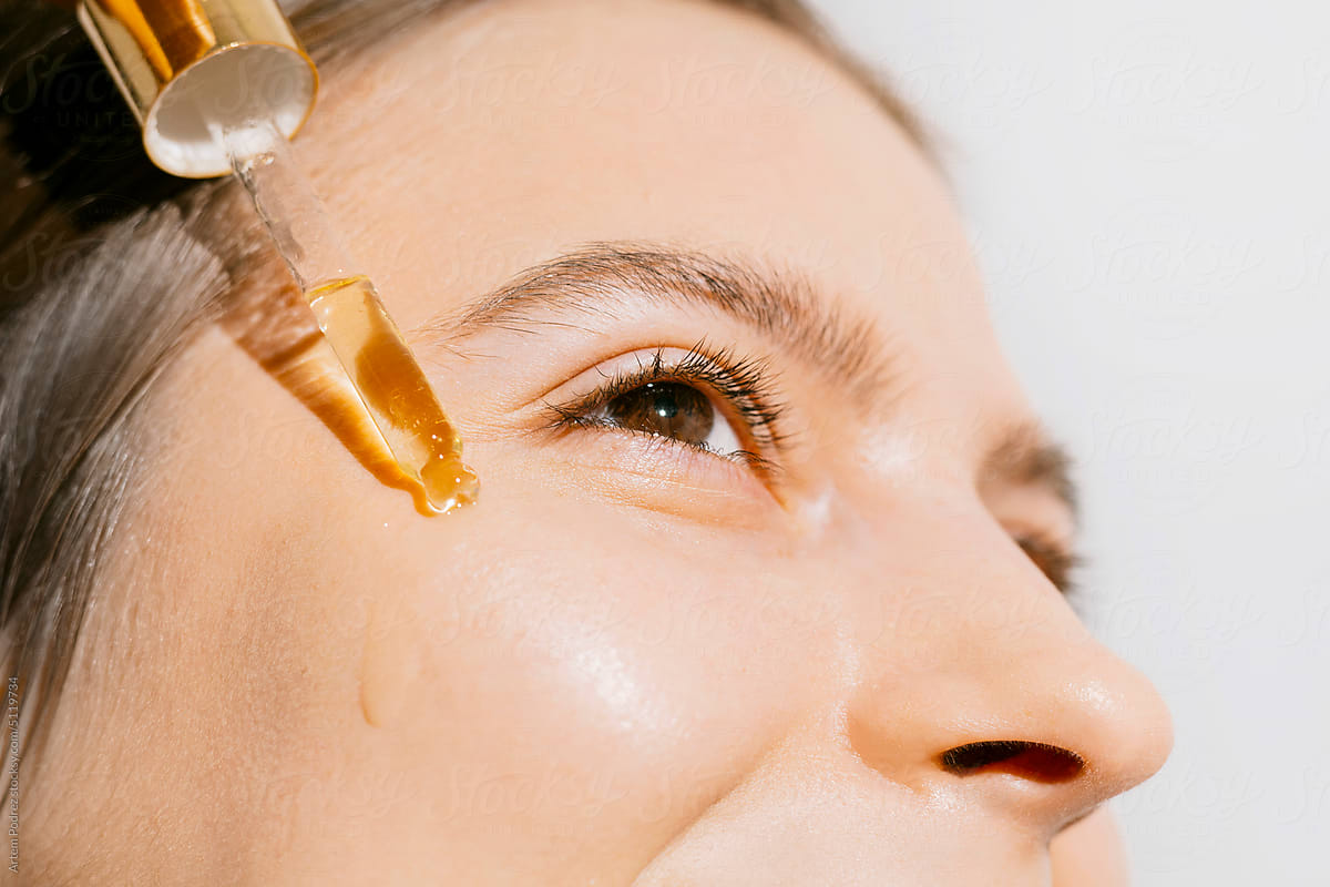 A young woman applying a face and body oil