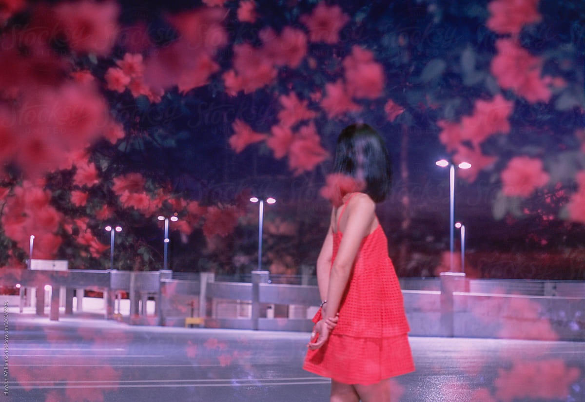 Woman in red dress among red flowers at night