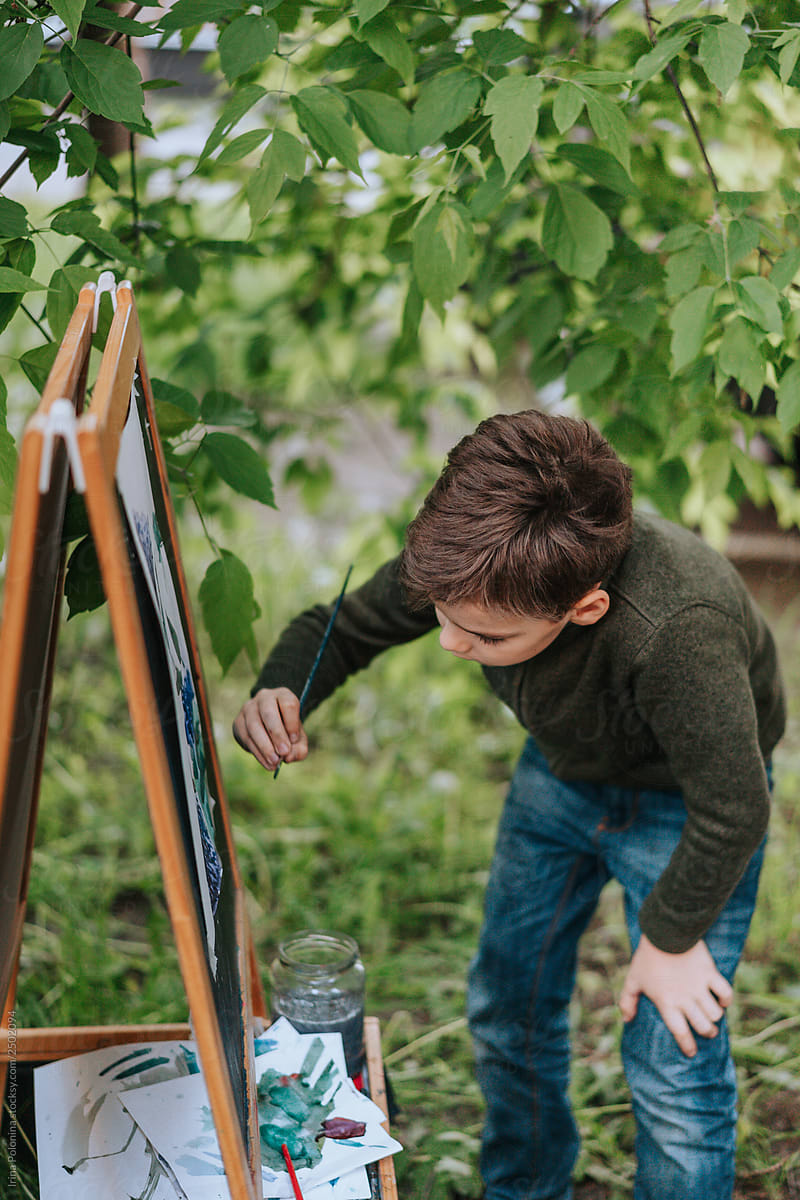 A young boy draws in the open air in the spring