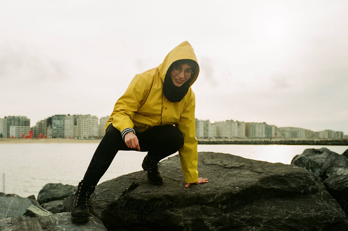 Woman wearing a yellow raincoat walk over a pier in a rainy afternoon