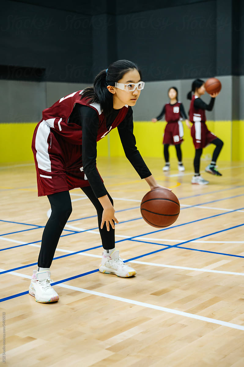 Teenage girl wearing basketball uniforms and doing drills at practice
