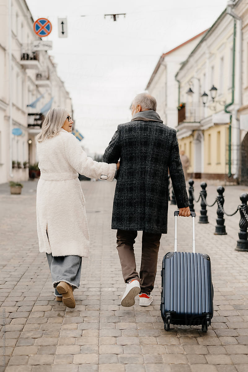 Senior couple with suitcase walking on street