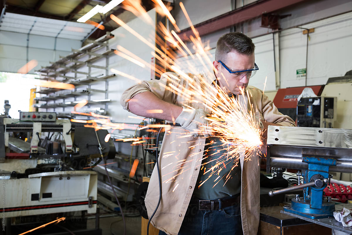 Sparks fly as man in facotry grinds metal