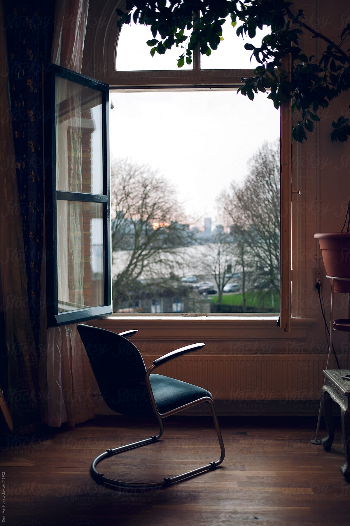 Empty chair in front of a open window with a view by Denni Van Huis