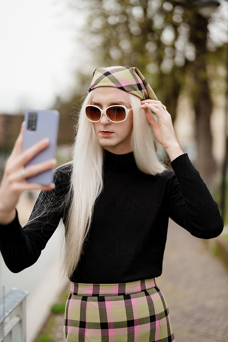 A stylish blond man using a smartphone for a selfie
