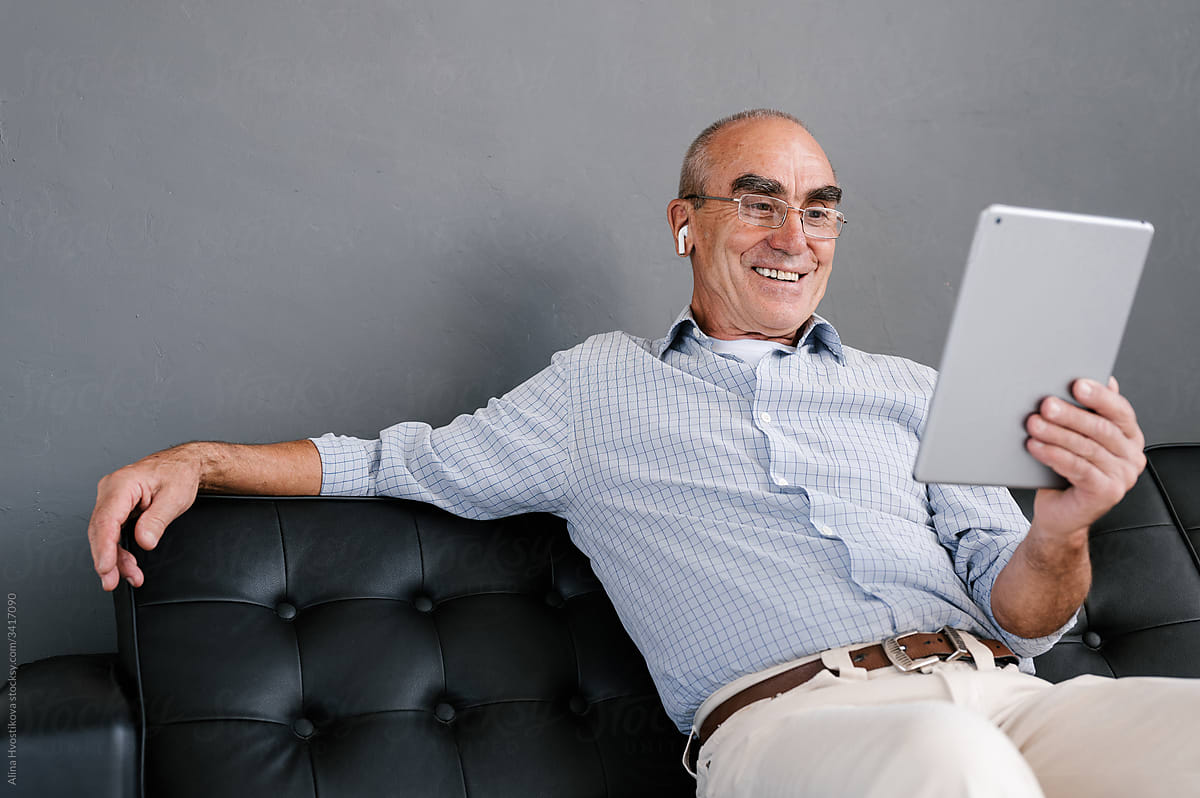 Cheerful senior man communicating online via tablet