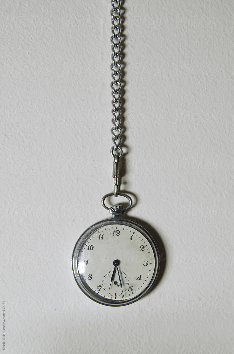 Old pocket watch hanging on the white wall