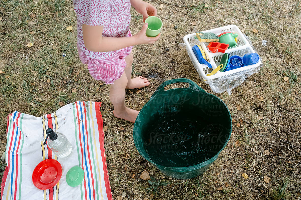 anonymous  girl playing with water and plastic dishes
