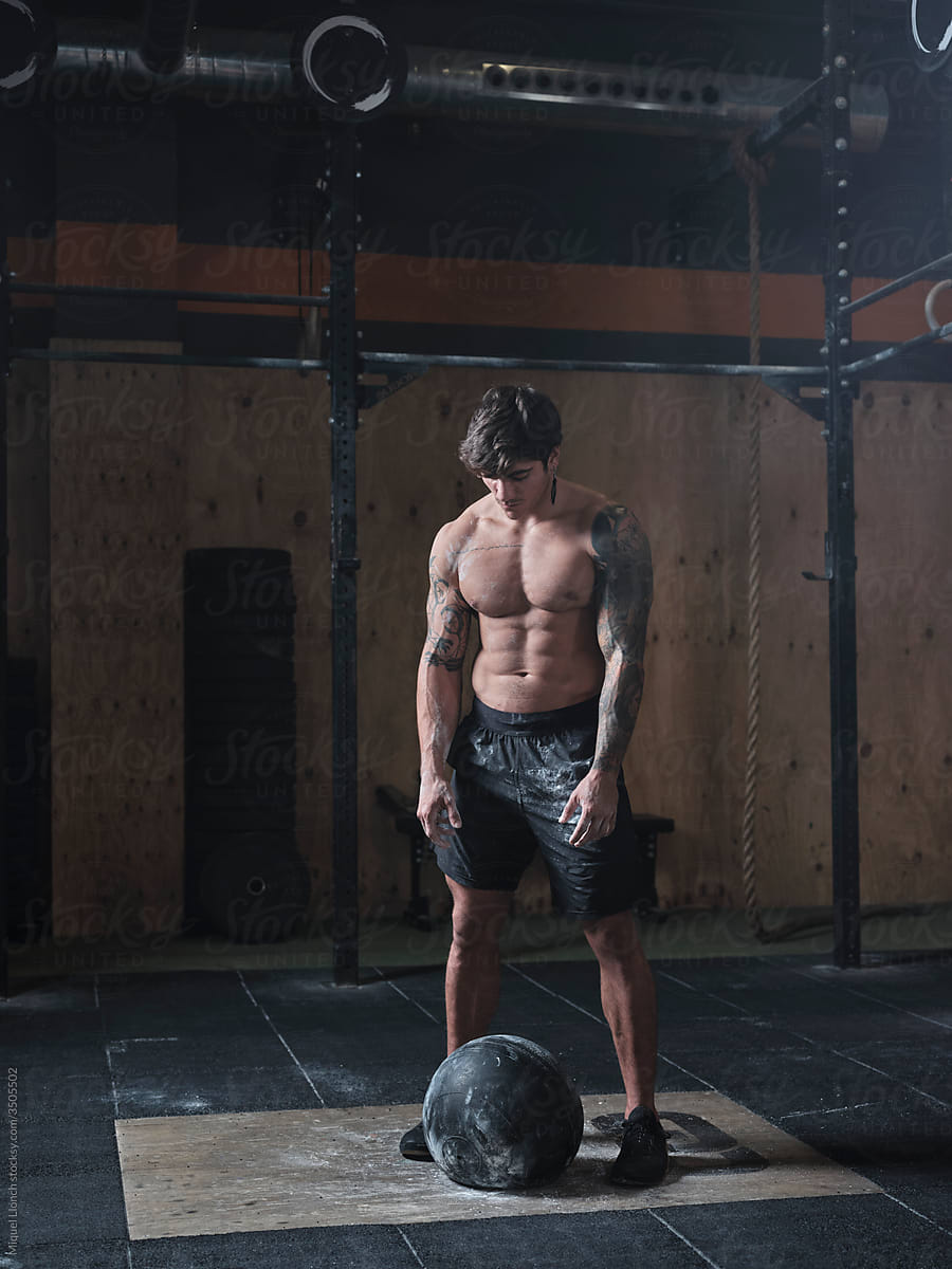 Young fit man with ball weightlifting