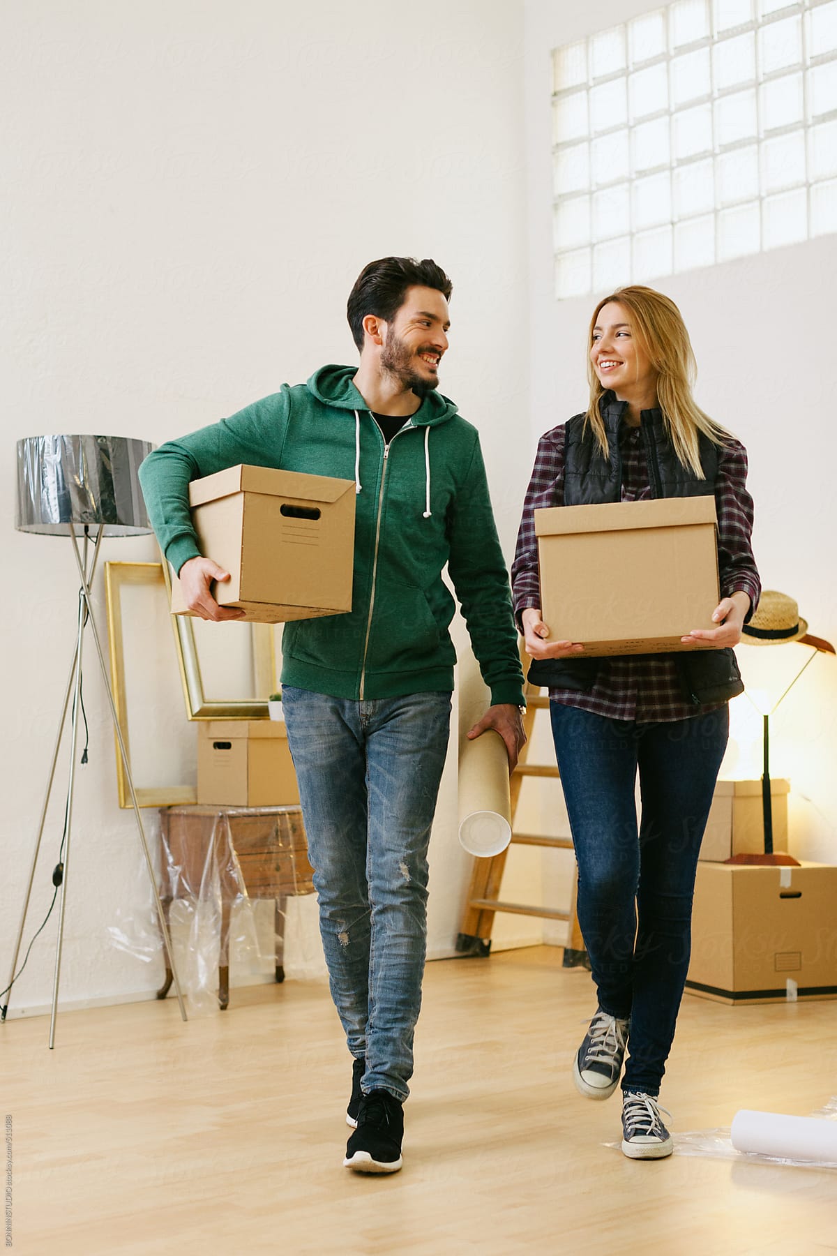 Young couple carrying boxes for moving into a new home.