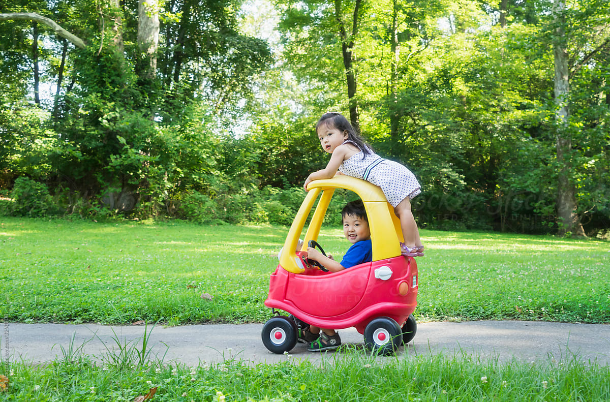 Asian Siblings Playing With Toy Car At Park By Stocksy Contributor