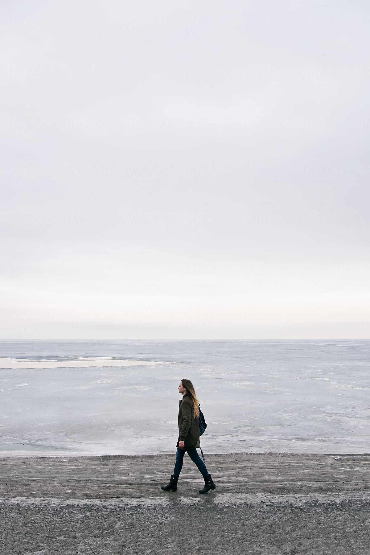 Long-haired woman walking along shoreline