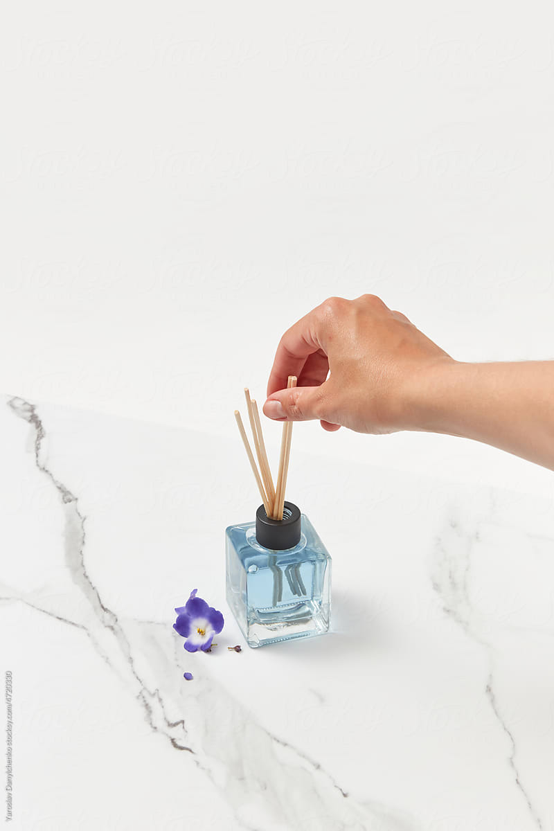 Female hand touching reed sticks of aroma diffuser.