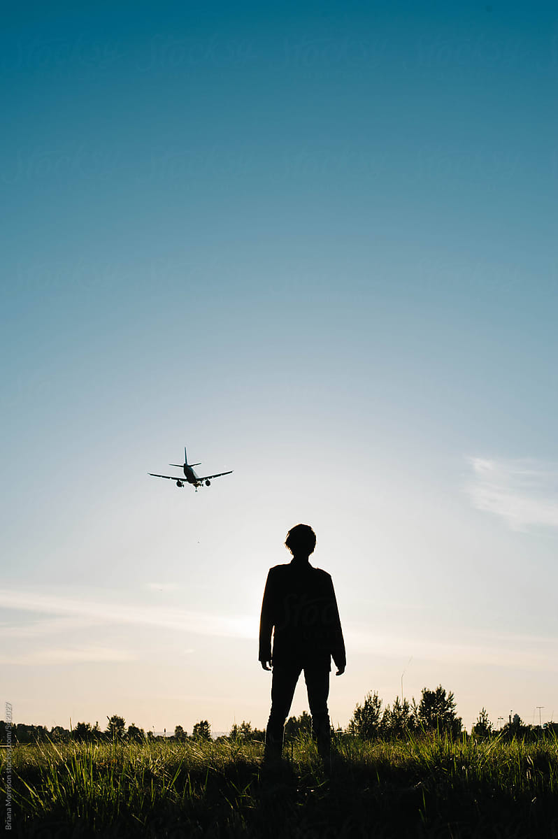Silhouette of a Man Watching a Plane in the Sky