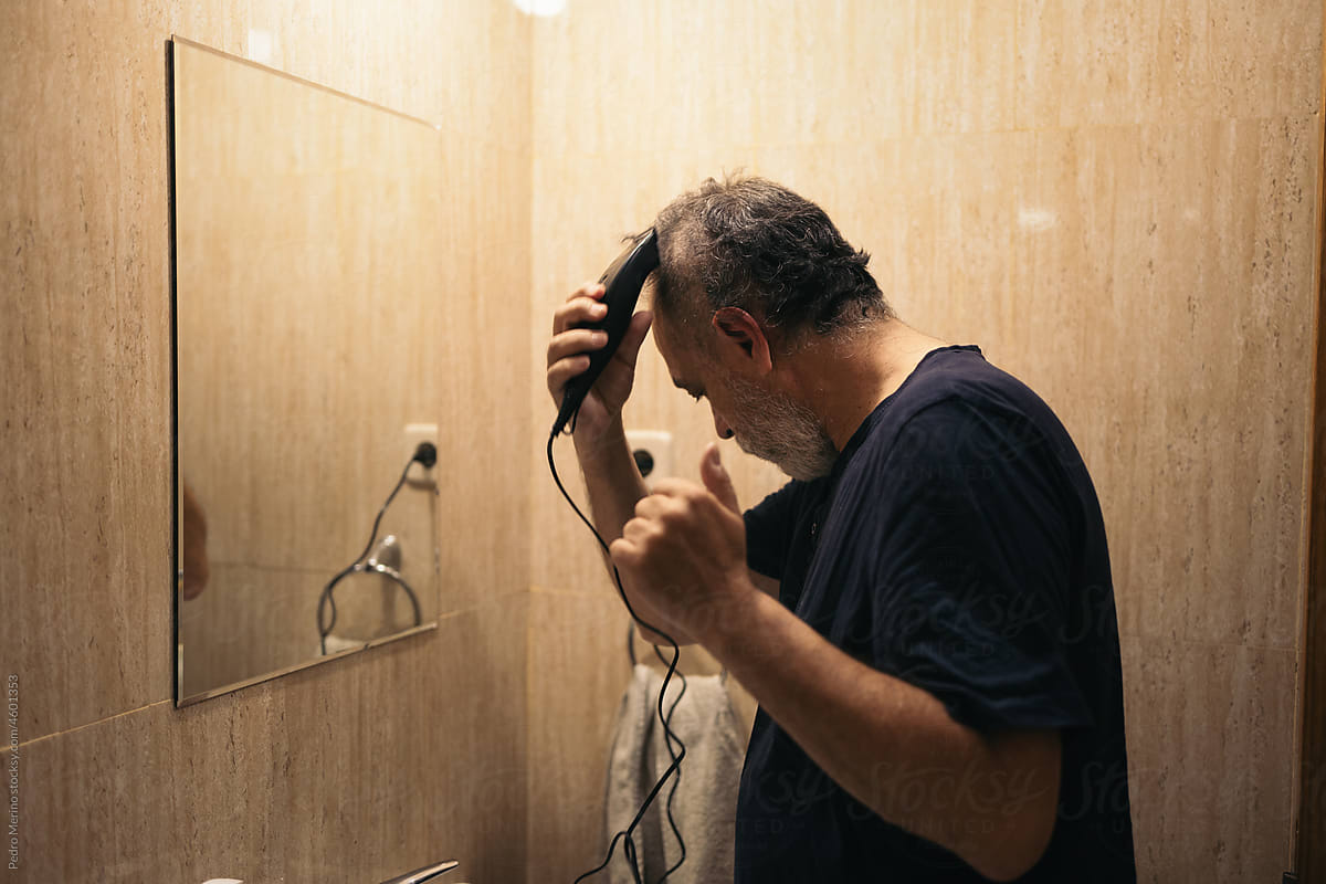 Mature man shaving his hair with a clipper