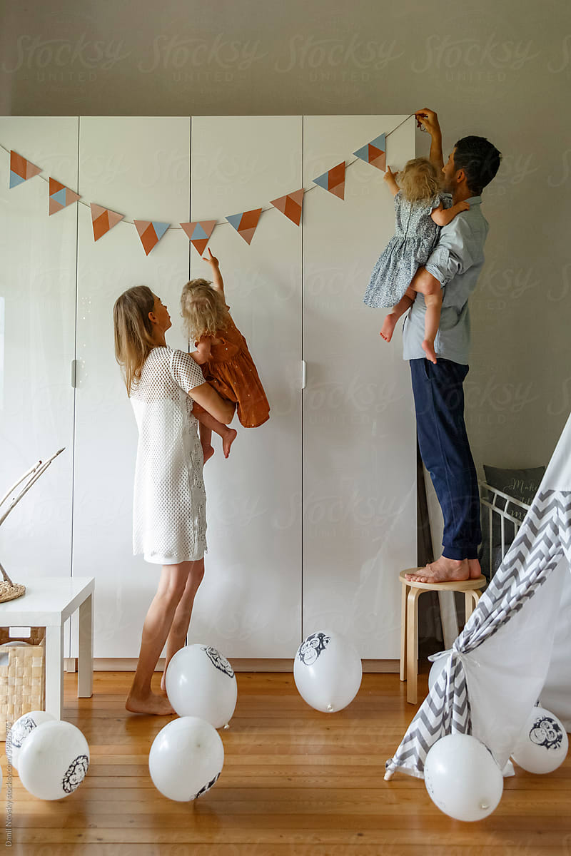 Parents with little kids decorating home for birthday party