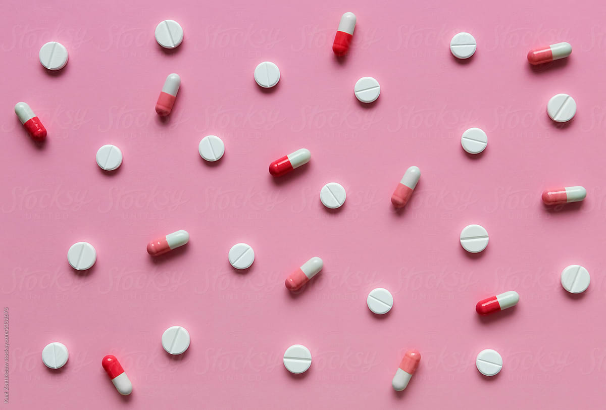 Various pink and white pills on a pink background