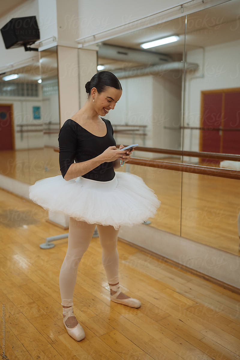 Smiling ballerina using smartphone after rehearsal