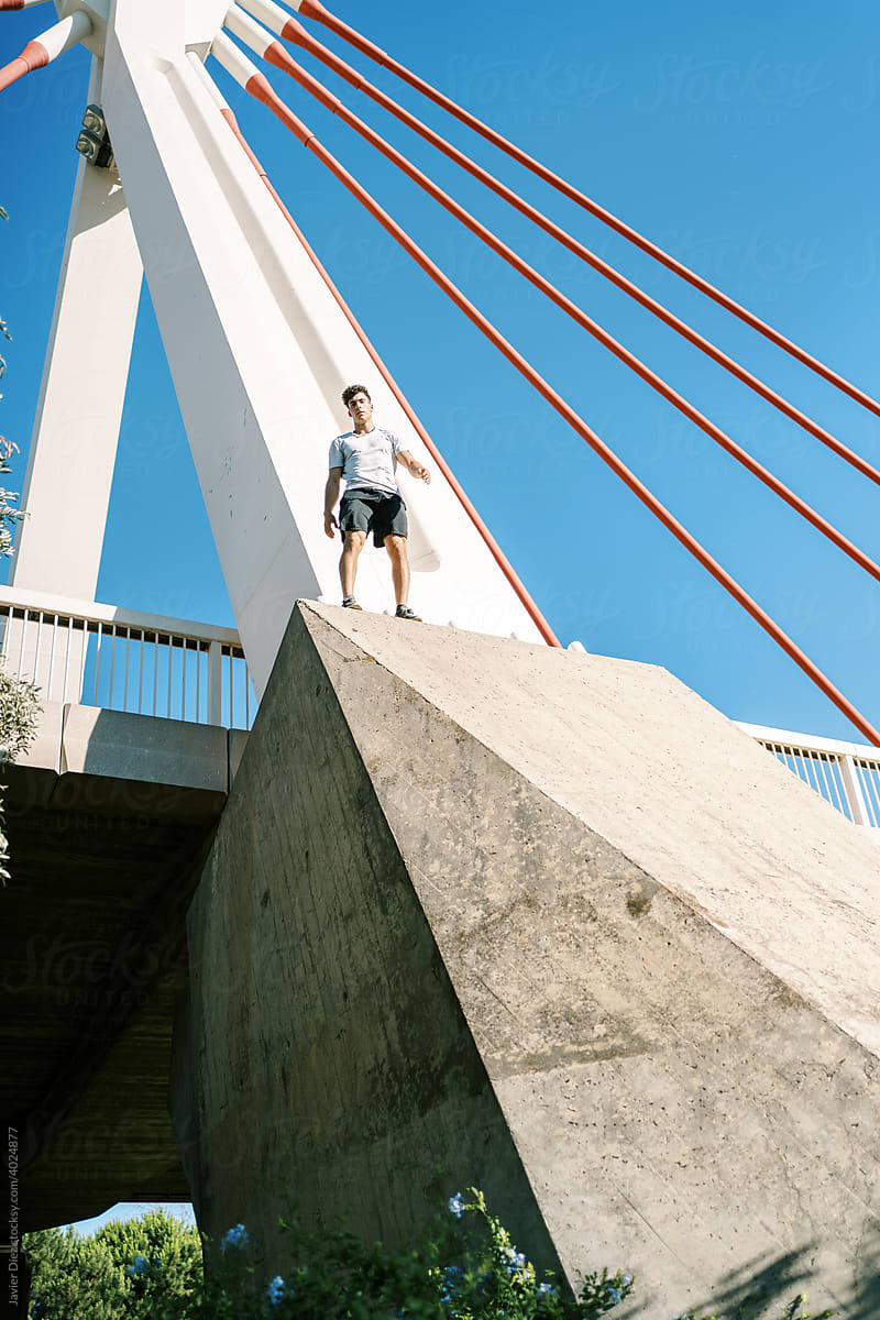 Young man climbing up bridge support