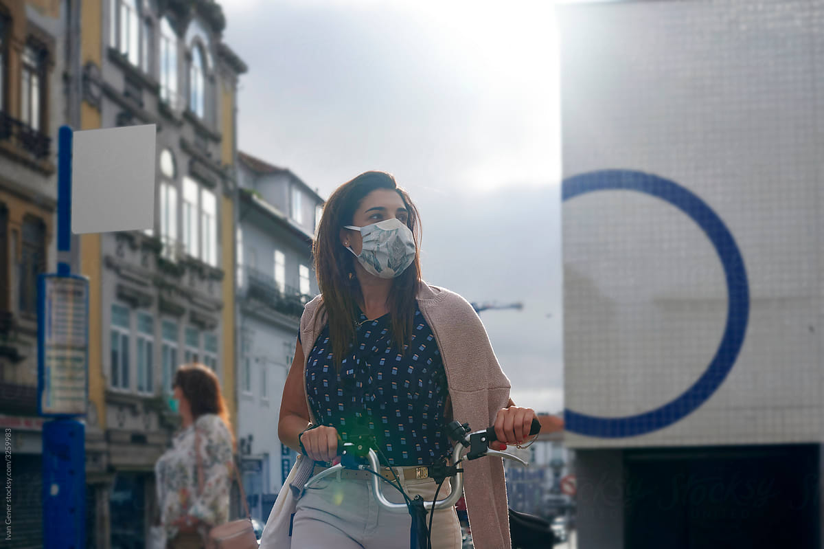 Woman in a face mask walking with a bike