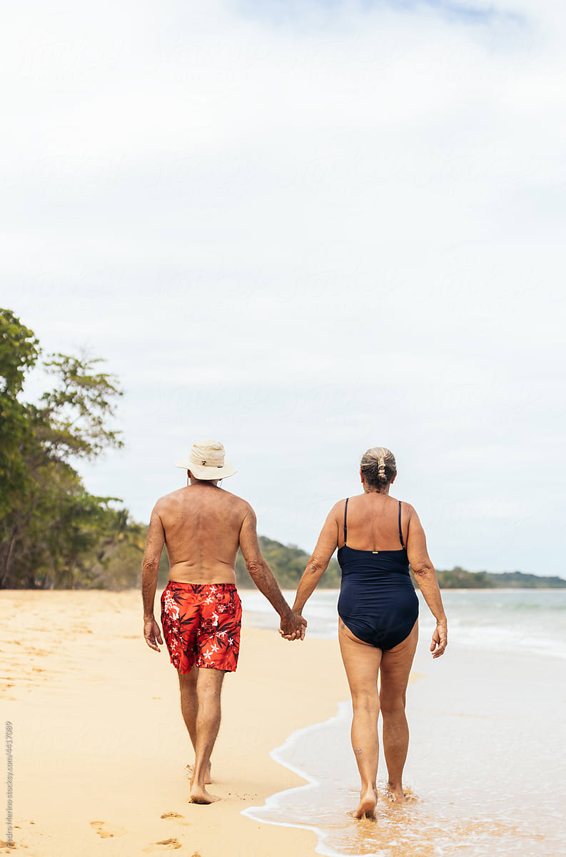 old couple from behind walking on the beach