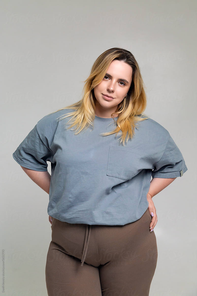 Happy young plus size woman standing with hands on waist