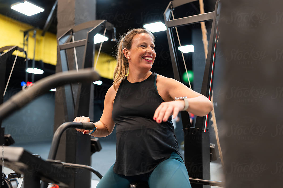 Smiling pregnant woman sitting on an air bike at the gym
