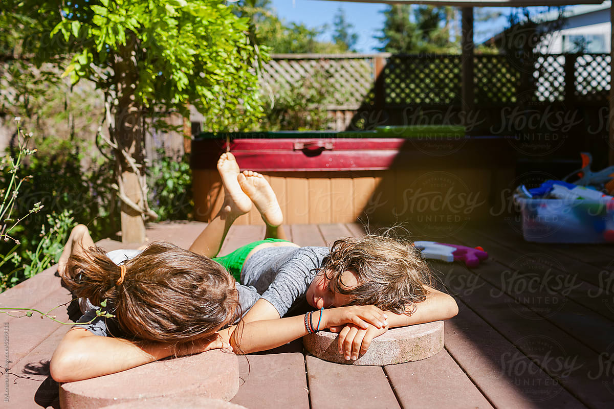 Children getting sun after getting wet with hose in backyard