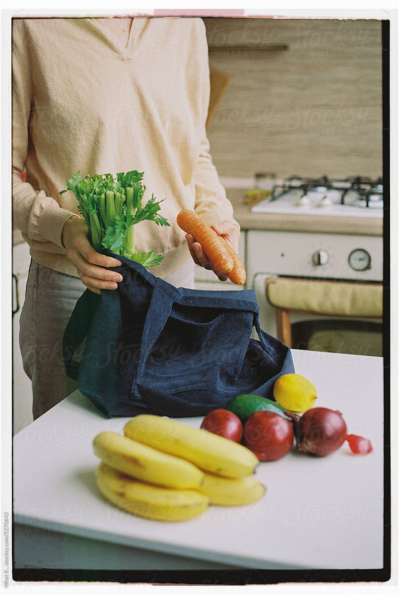 Unrecognizable woman in the kitchen takes groceries out of her bag.