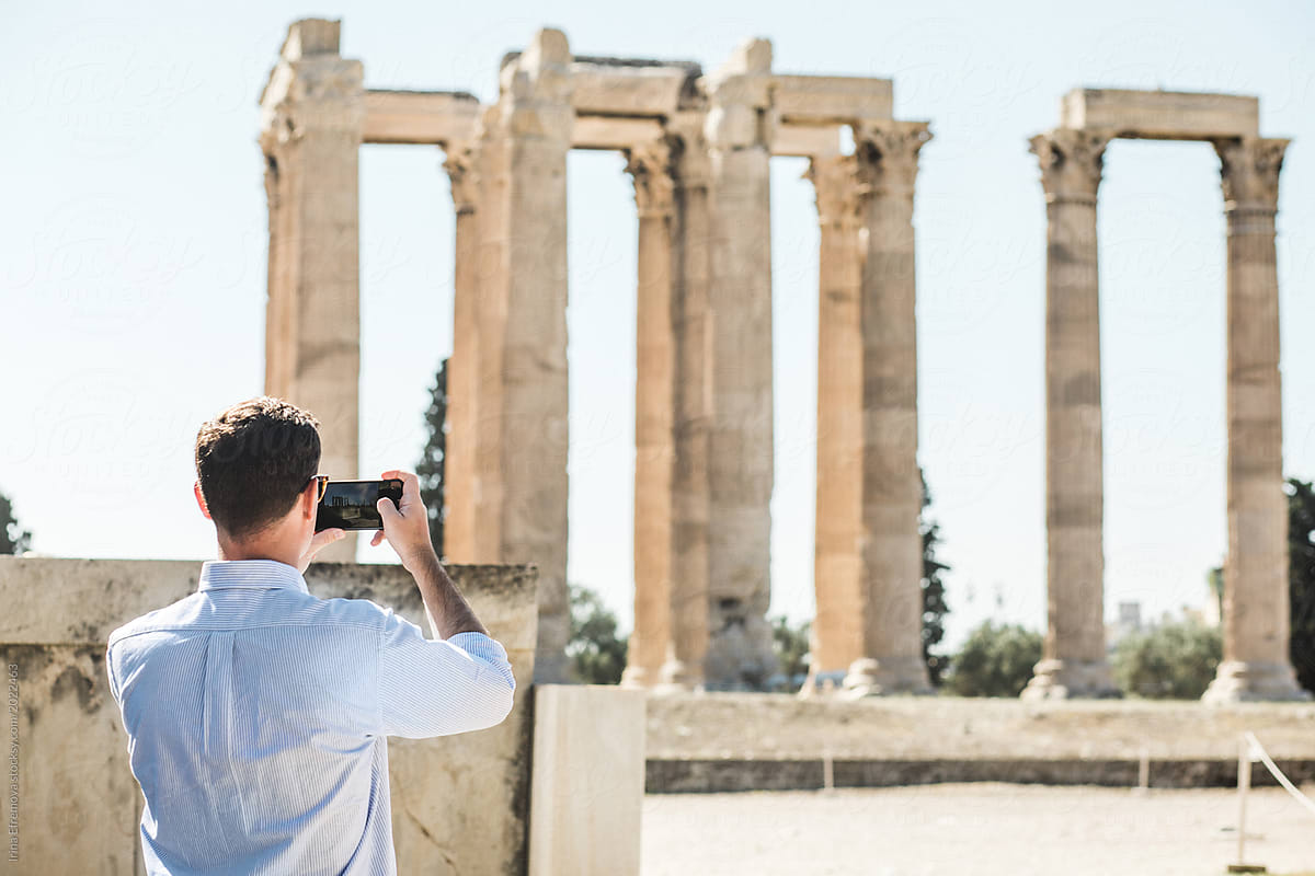 Caucasian Man taking a photo of an ancient temple in Athens, Greece