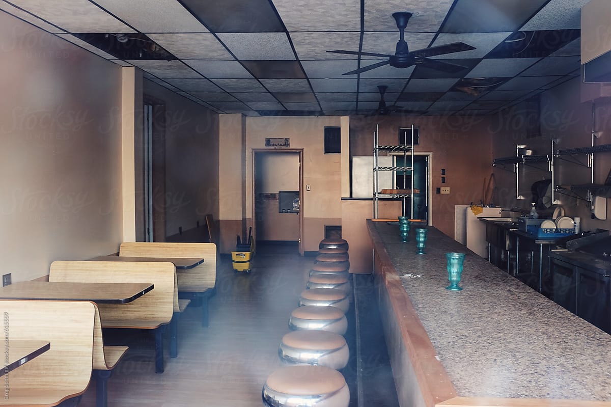 An abandoned, empty diner restaurant with booths and stools and a counter