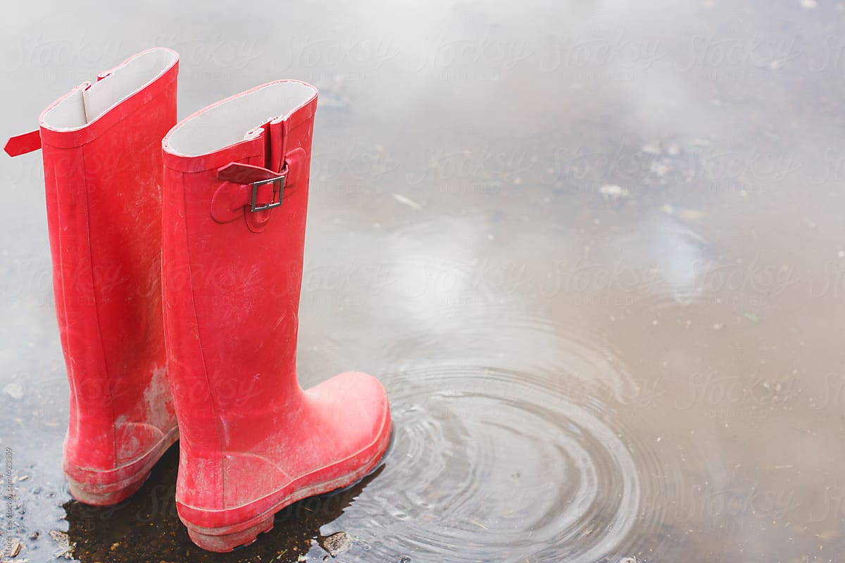 Pair of red rubber boots in a puddle